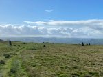 Mitchell's Fold stone circle from a distance, on a summer's day with white clouds and blue sky