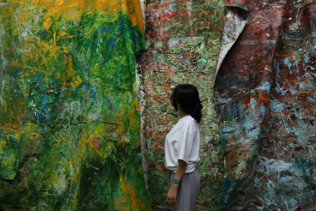 Korean woman with dark hair stood in front of large scale abstract paintings