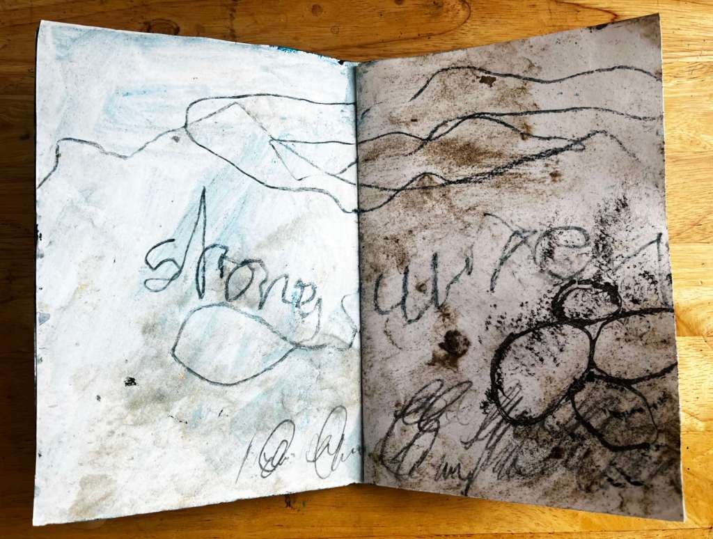 An artists book with marks and handwriting suggesting a coastline